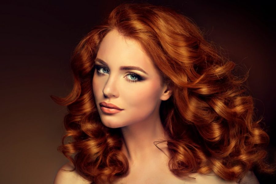 Girl model with long red wavy hair. Big curls on the red head . Hairstyle  permanent waving