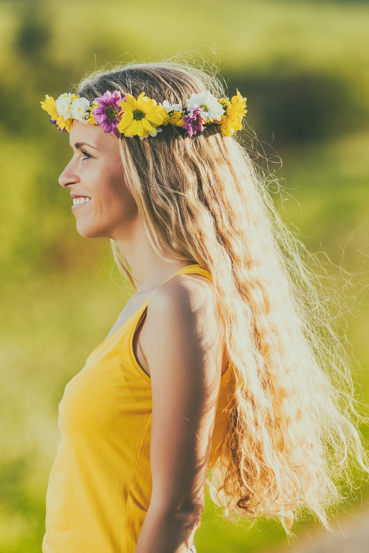 Beautiful woman with wreath on her blonde hair enjoys in the nature.